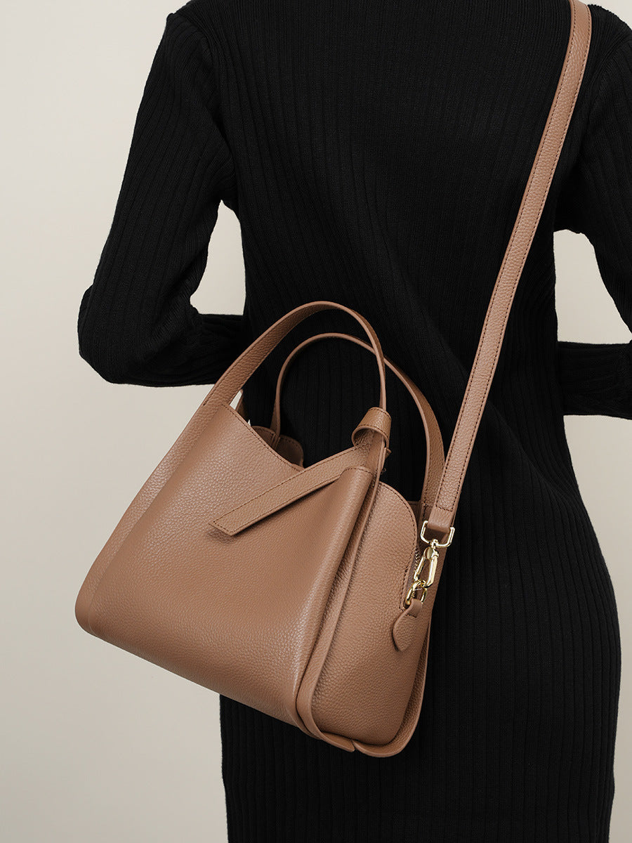 Khaki bucket bag worn crossbody with adjustable strap and gold clasp