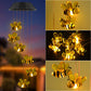 Yellow glowing bee figures hanging from a solar lamp head at dusk, with close-ups of the lit bees