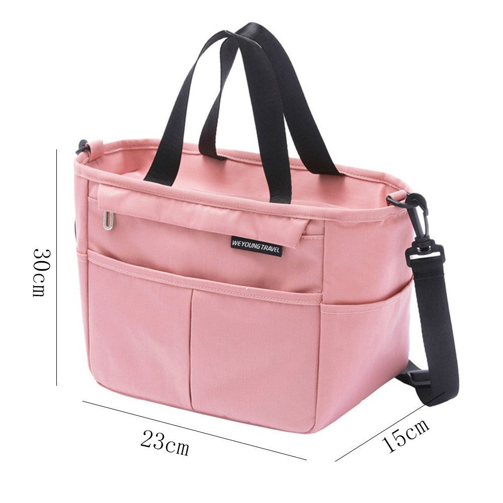 Insulated lunch bag carried by its two webbing handles, boxy shape with a flat wide base