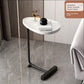 White marble look oval top on a black framed C shaped side table on a grey stone floor