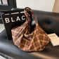 Woolen plaid tote worn on the shoulder showing the adjustable buckled strap and roomy body