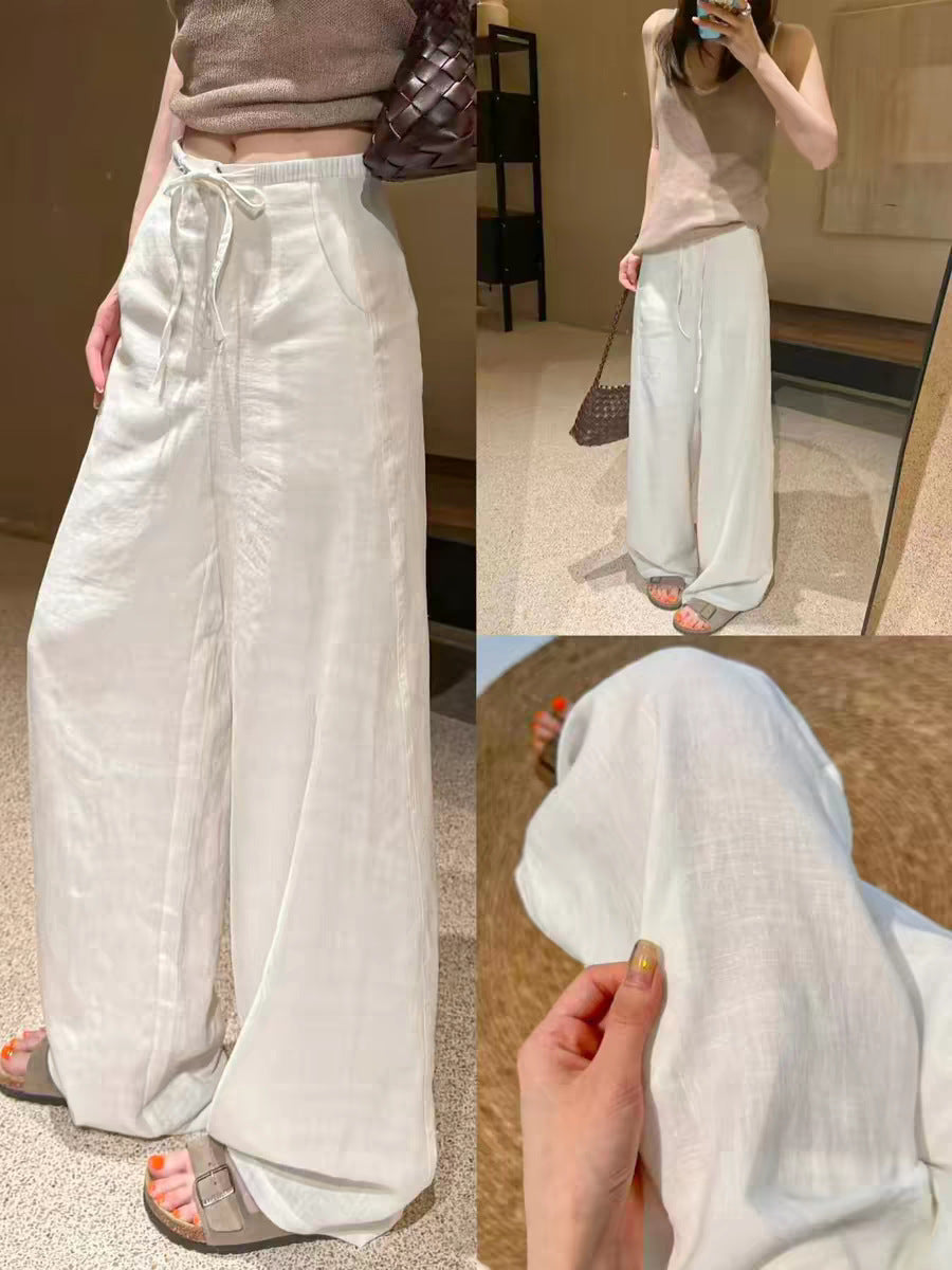 Womens high waist wide leg linen blend drawstring trousers, shown full length on a standing model with a woven bag