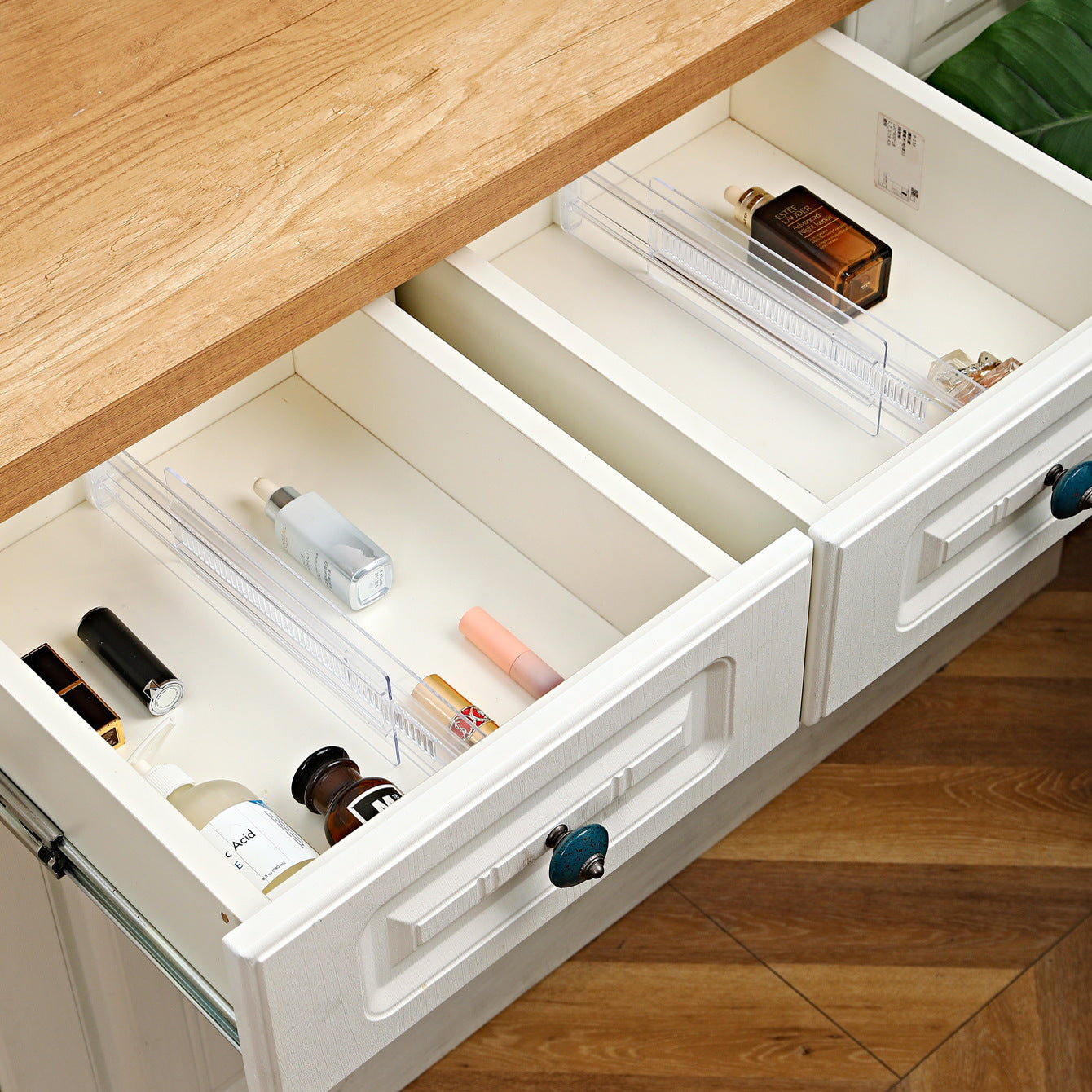 Clear drawer dividers organizing cosmetic bottles and tubes inside white dresser drawers