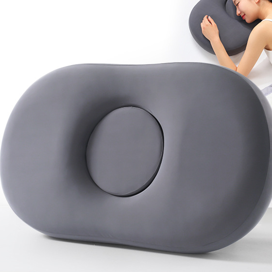 Dark gray oval memory foam pillow with round center hole shown beside a person resting