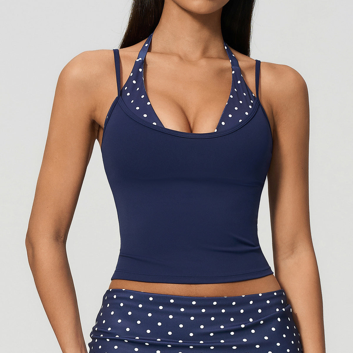 Model in a cropped camisole with a printed halter inset, navy with white polka dots