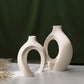Set of two white nesting ceramic vases with a curved hollow silhouette