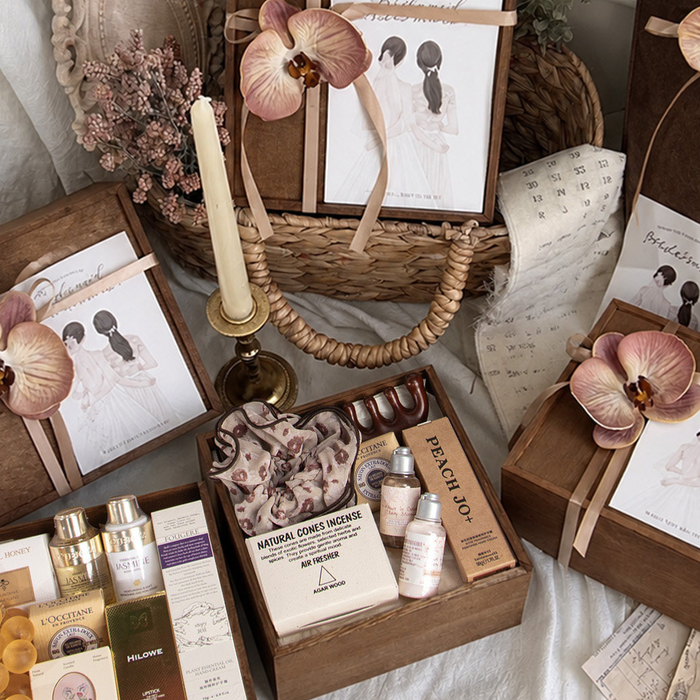 Wooden gift boxes with a ribbon and brown orchid flower, illustrated bridesmaid cards and gifts beside a candle