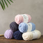 Merino Wool labelled yarn ball in light pink wound neatly on a wooden table