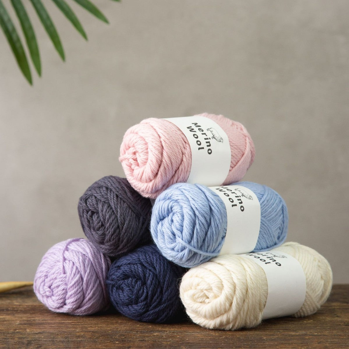 Merino Wool labelled yarn ball in light pink wound neatly on a wooden table