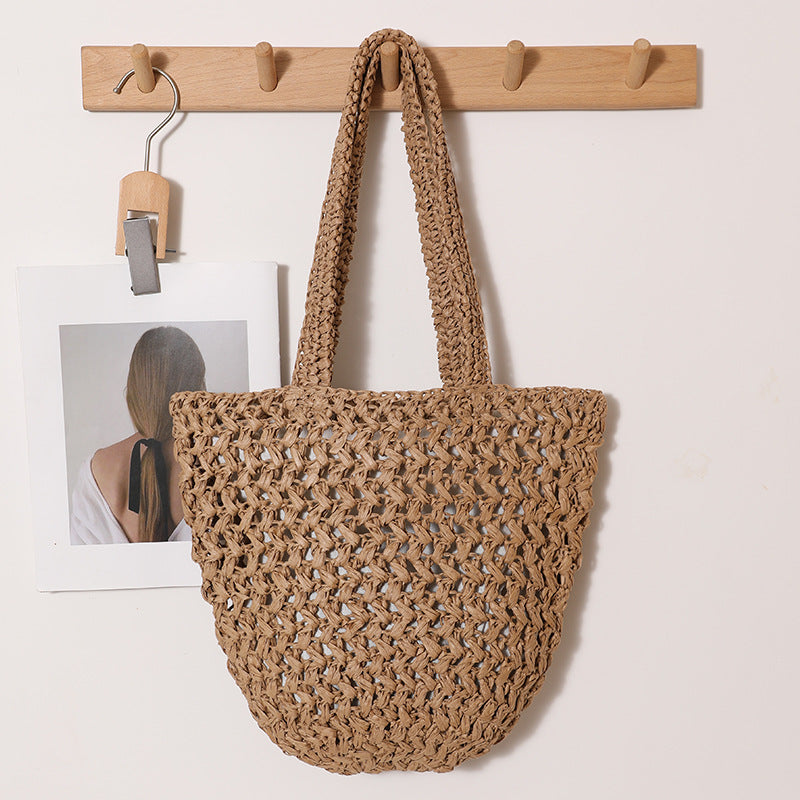 Tan paper straw shoulder bag showing open crochet weave and U-shaped base on a peg rack