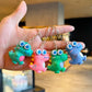 Cartoon dinosaur keychain charm shown in hand for size reference