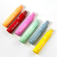 Six GlorySmile fluoride toothpaste tubes lined up in watermelon, mango, coconut, mint, peach and red velvet