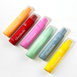 Six GlorySmile fluoride toothpaste tubes lined up in watermelon, mango, coconut, mint, peach and red velvet