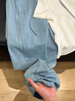 Close view of light blue jeans leg and hem showing soft lightweight denim drape