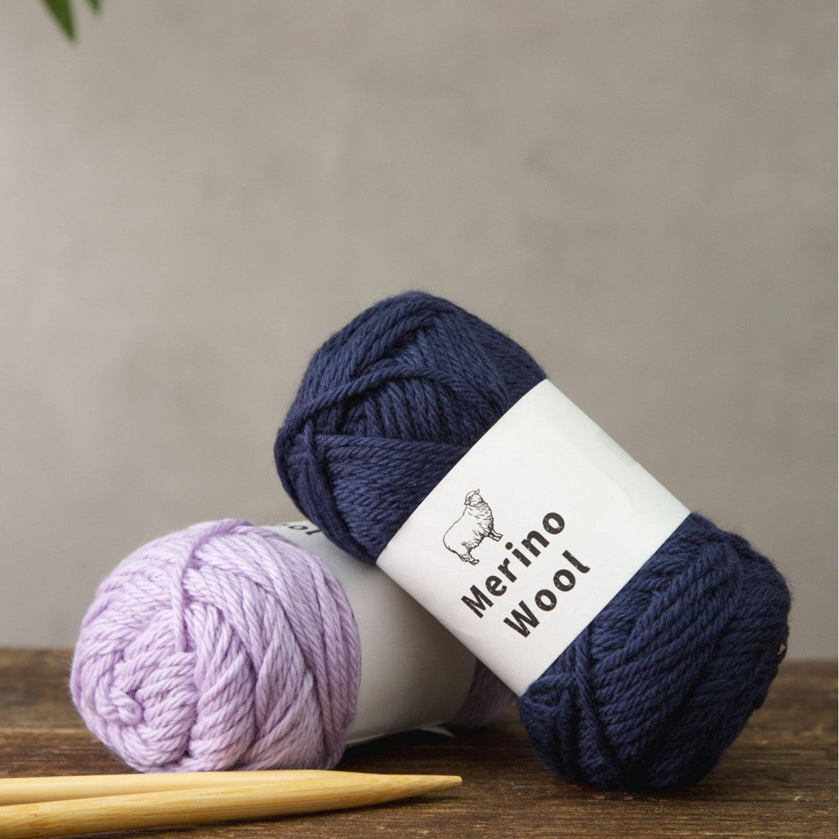 Stacked balls of merino wool yarn in pink, blue, purple, navy and cream shades
