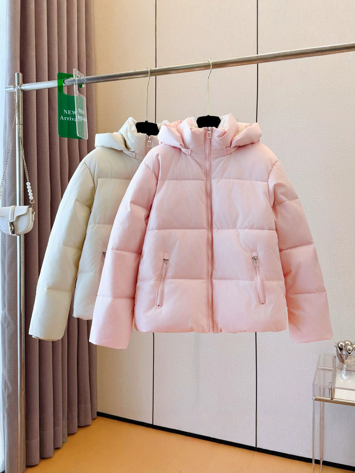 Women's short hooded puffer jacket with a padded quilted shell and full front zip on a hanger