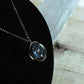 Starfield face of the glass ball pendant on its chain, shown against a dark display curve