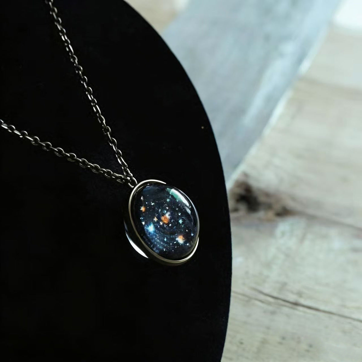 Starfield face of the glass ball pendant on its chain, shown against a dark display curve