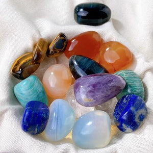Assorted tumbled gemstone pebbles gathered in a round ceramic bowl