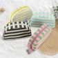 Striped canvas toiletry bag with top zip closed on a plain background