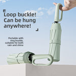 Light green folding umbrella with a loop buckle handle held in the hand
