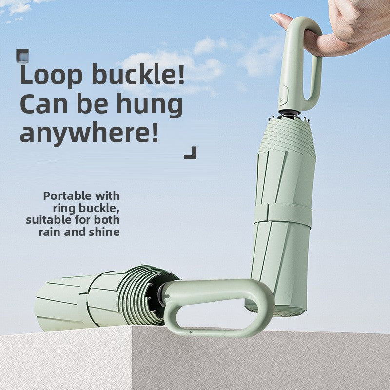 Light green folding umbrella with a loop buckle handle held in the hand