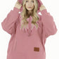 Pink sherpa fleece pet pouch hoodie on a woman with the drawstring hood raised