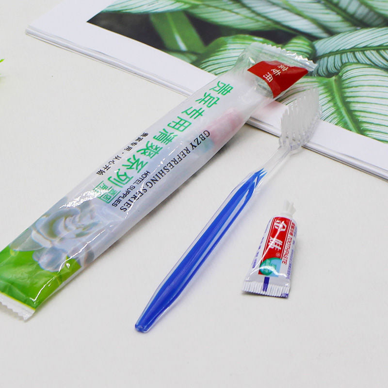 Blue plastic toothbrush with a toothpaste tube and a hotel supplies pouch on a light surface