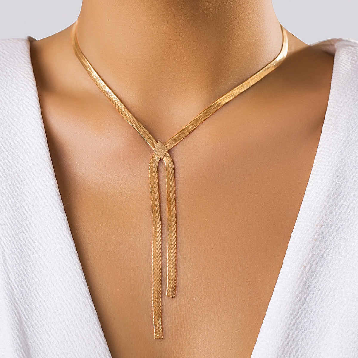 Gold snake chain lariat necklace with two flat chain ends on a model