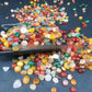 Hand holding a scoop of colourful polished agate pebbles for scale