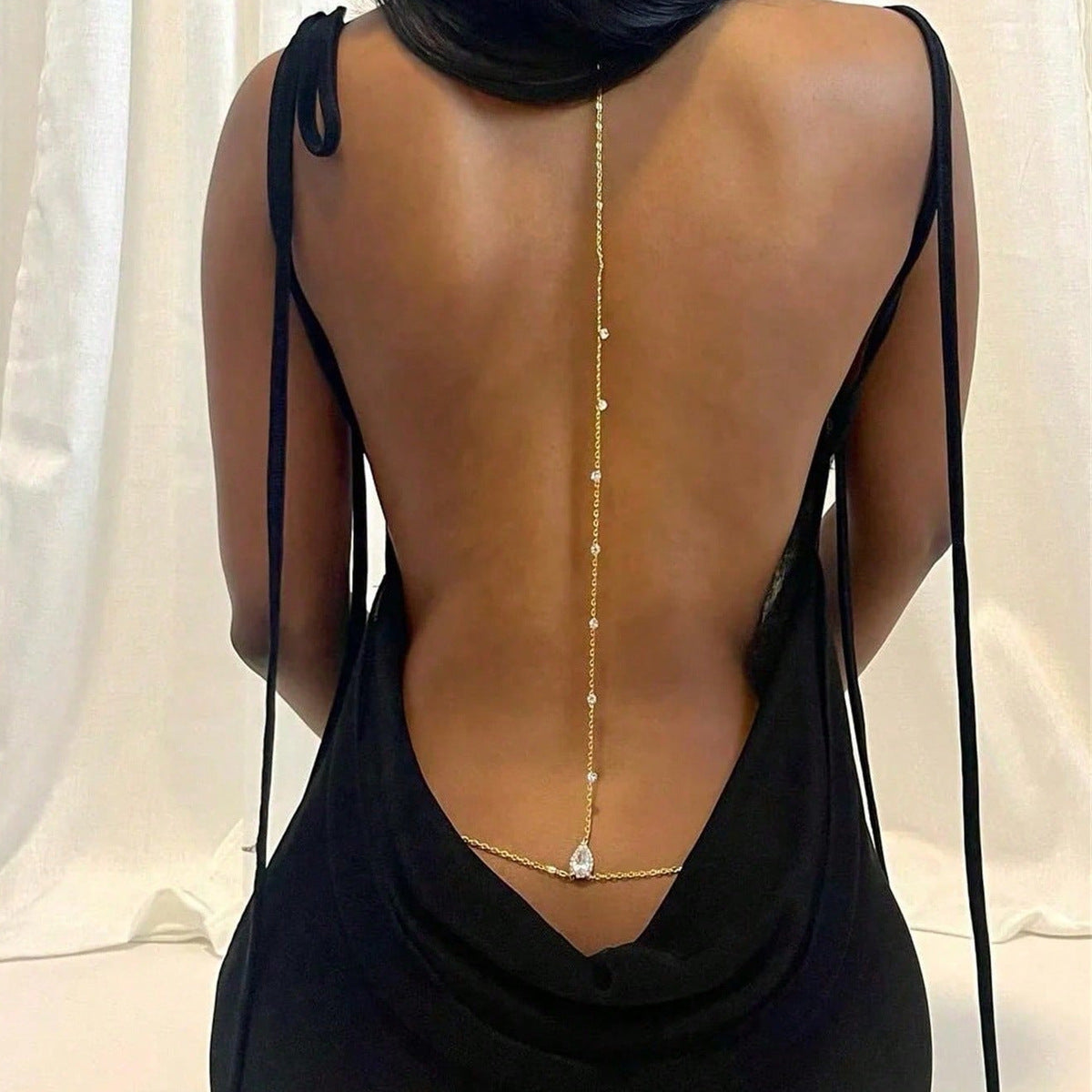 Gold back chain with crystal accents and a teardrop on an open back