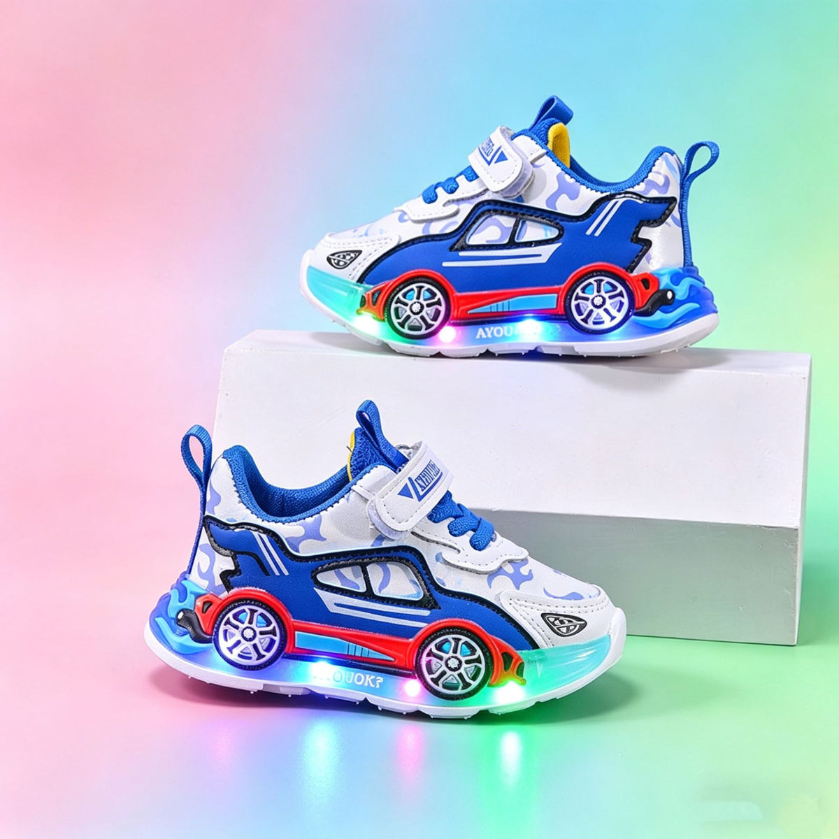 Blue and white sports car kids sneakers with LED sole lights on a pastel rainbow background