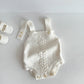 Baby knit cotton romper held to show its small infant size and scale