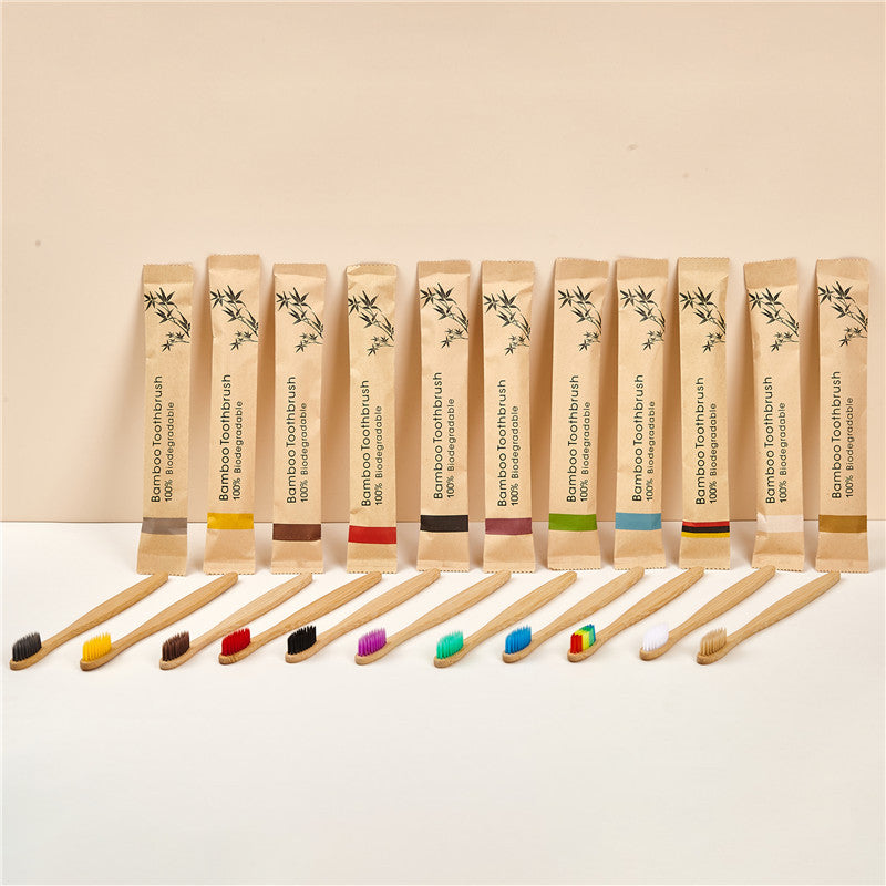 Row of bamboo toothbrushes with colored soft bristles beside kraft paper sleeves