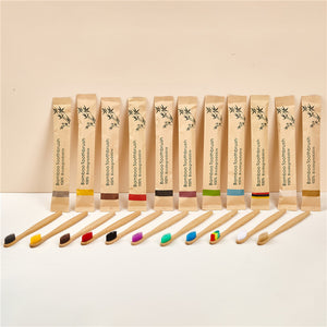 Row of bamboo toothbrushes with colored soft bristles beside kraft paper sleeves