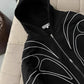 Model wearing a black embroidered zip up hoodie seen from behind