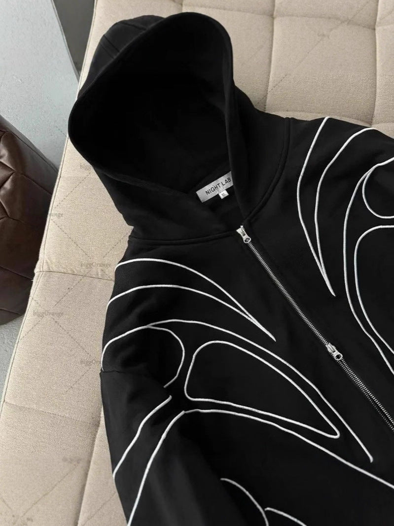 Model wearing a black embroidered zip up hoodie seen from behind