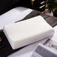 White knitted cover contour latex pillow resting on a made bed