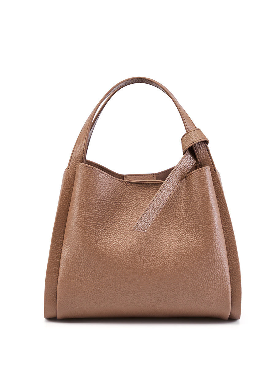 Khaki cowhide bucket bag front view with rolled top handle and leather tab