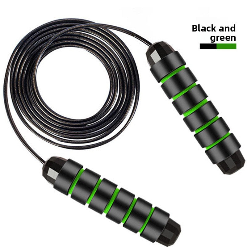 Black and green skipping rope laid flat on white with the coated steel cable coiled