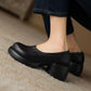 Black PU slip-on pump with rounded sculpted heel and platform sole seen from the front on a beige wool carpet