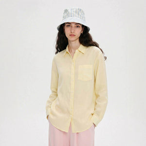 Woman in a light linen button-up shirt worn open, front view showing lapel collar and placket