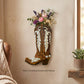 Brown wooden boot wall vase with cream inlay mounted on a plaster wall with dried stems