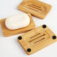 Bamboo soap dish holding a white soap bar beside two more slotted bamboo dishes