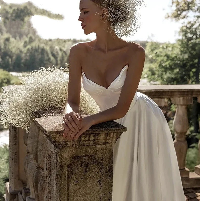 Strapless satin wedding gown with a small sweep train trailing on a path