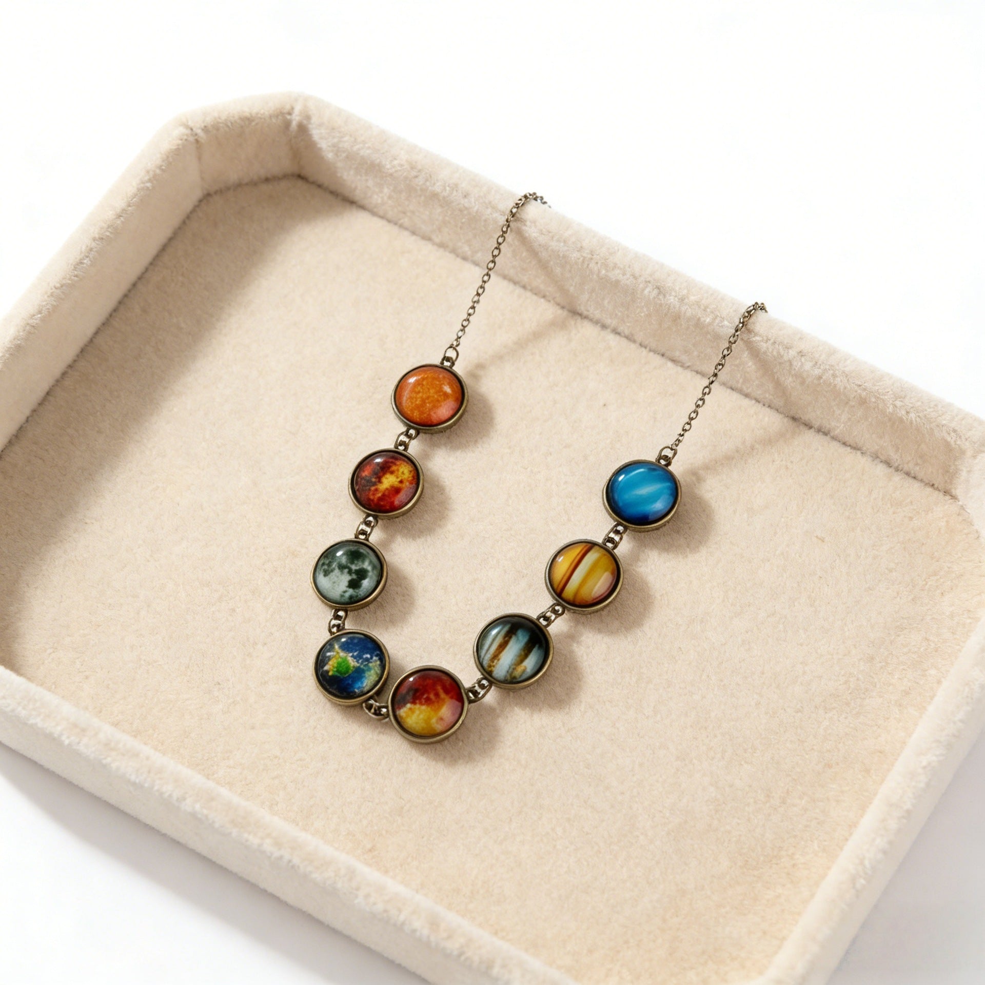 Solar system necklace in a cream velvet jewellery tray, eight domed cabochons linked edge to edge
