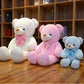 Cream white, pink and light blue plush teddy bears with striped bow ties sitting in a row in front of a bookshelf