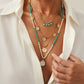 Gold layered bohemian necklace with turquoise beads worn over an open shirt