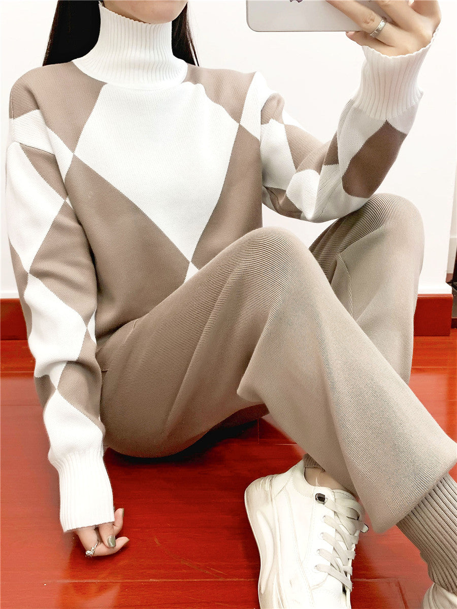 Model in a khaki and white argyle high neck sweater and khaki knit pants sitting on a red floor taking a mirror photo