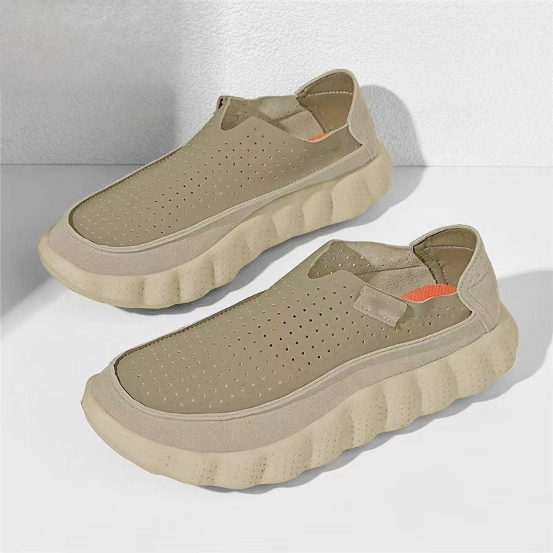 Pair of khaki perforated slip-on loafers with a cream scalloped sole and an orange insole on a white stepped studio set